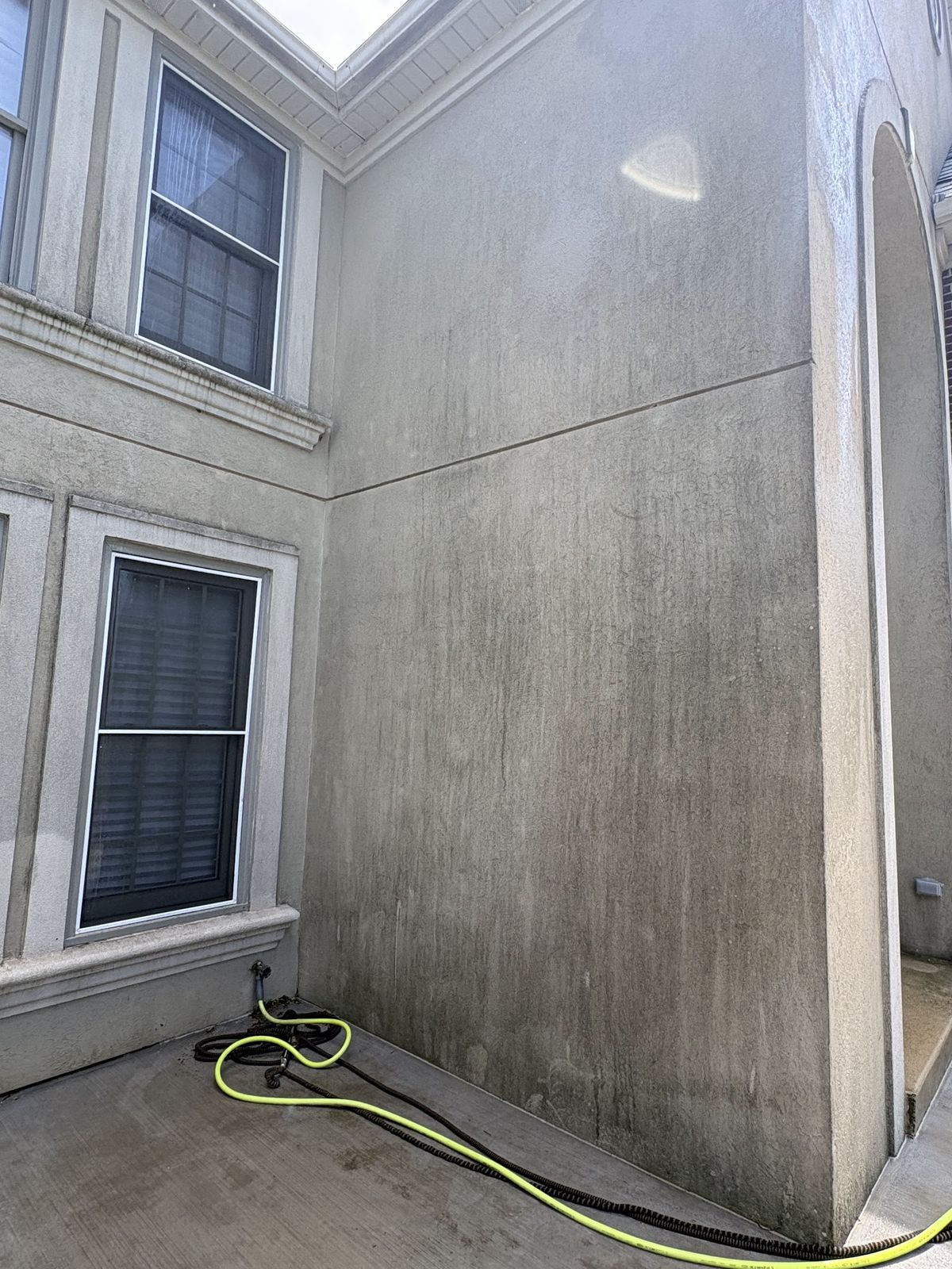 Stucco wall darkened with grime before cleaning